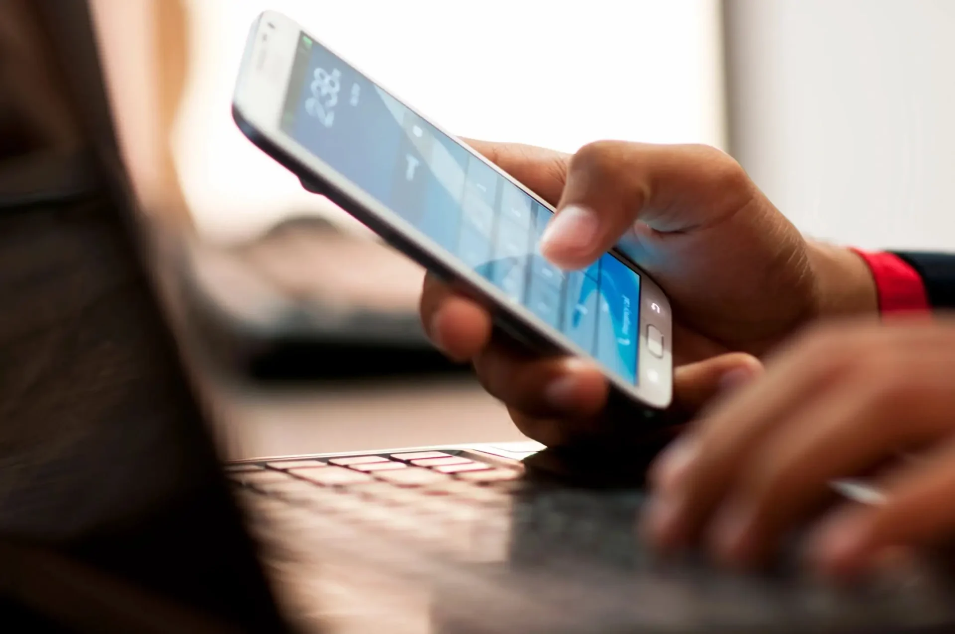 A person is using their phone while sitting at the keyboard.